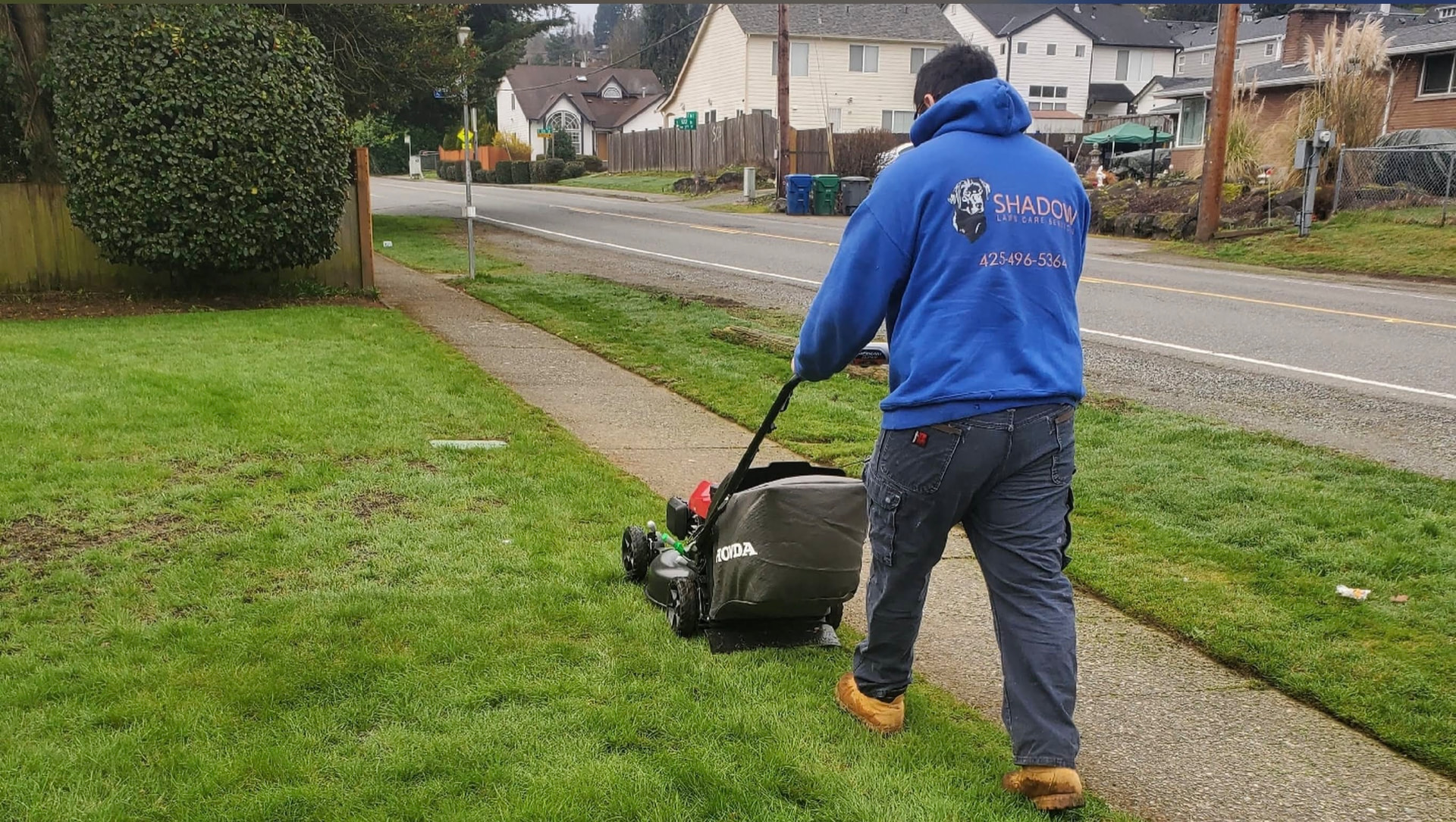 Shadow Lawn Care crew mowing a lawn along a sidewalk